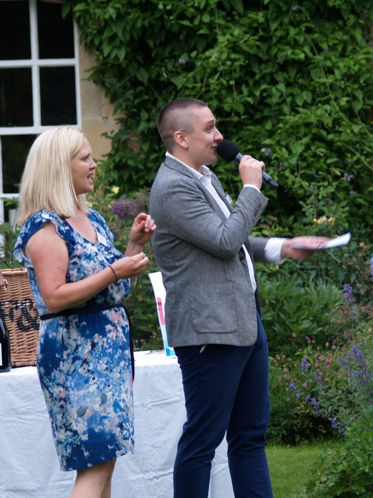 Man and woman laughing, giving out raffle prizes. Man is holding a microphone