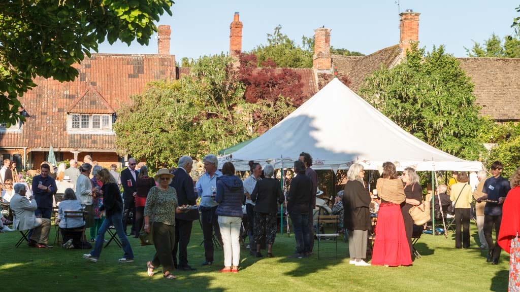 A garden party with a marquee and people standing around